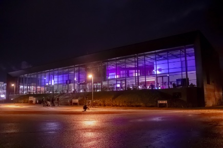 Außenaufnahme vom Audimax der Uni Lübeck bei Nacht. Das Audimax ist lila beleuchtet.